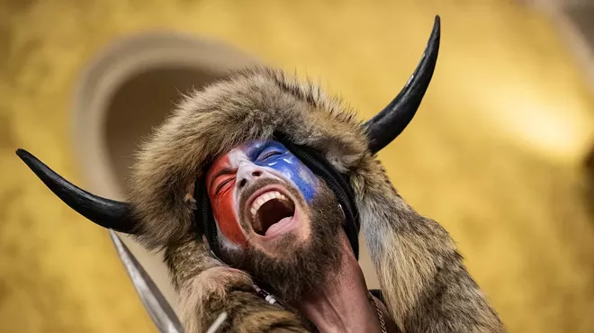 the qanon shaman, with a buffalo headdress and red-white-and-blue facepaint