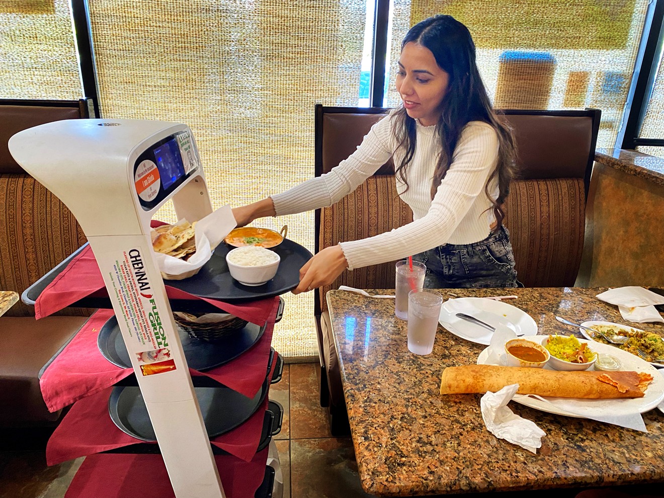 Joty Kaur of Litchfield Park lifts her dish from Shiela, the robot server at Chennai Fusion Grill in Chandler.