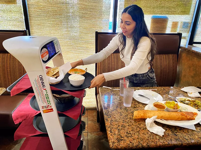 Image: Joty Kaur of Litchfield Park lifts her dish from Shiela, the robot server at Chennai Fusion Grill in Chandler.