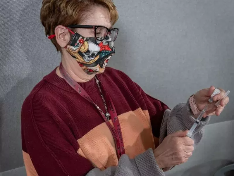 Image: A health care worker prepares to administer a COVID-19 vaccination shot.