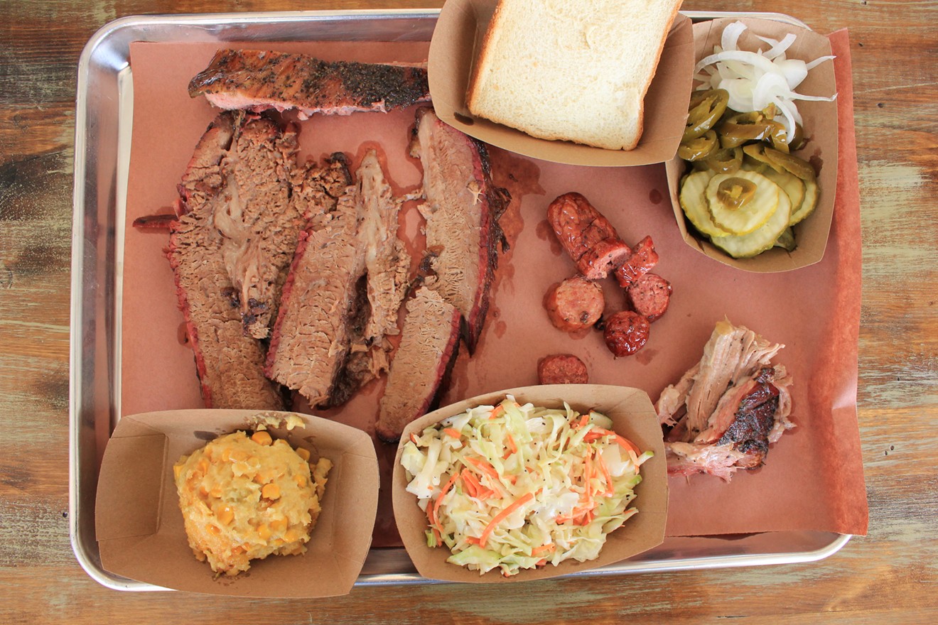 A platter of brisket, sausage, pulled pork, a rib, and sides.