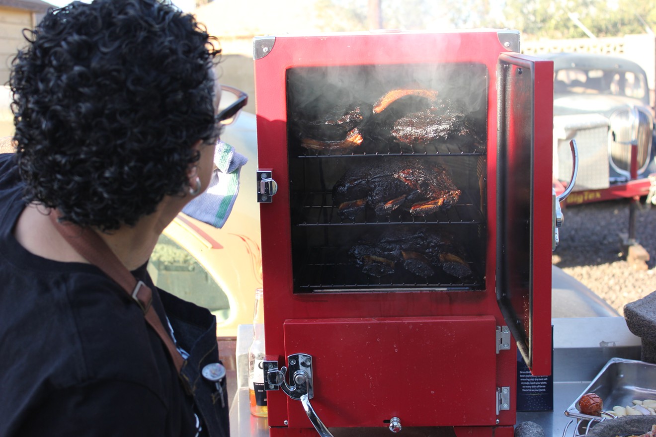 Checking on beef short ribs and pork ribs in an upright smoker