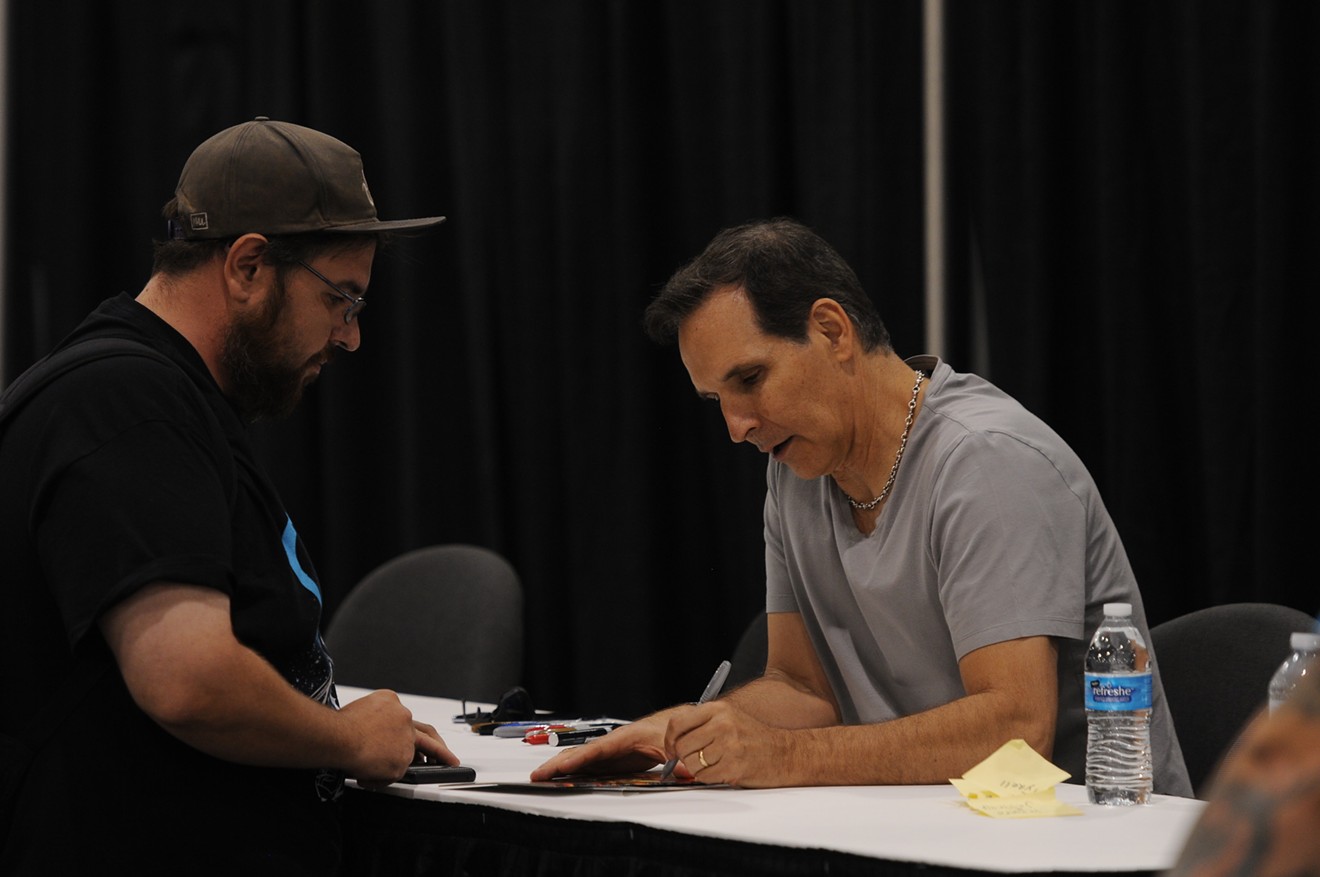 Famed comics creator Todd McFarlane signs an autograph in the Hall of Heroes.