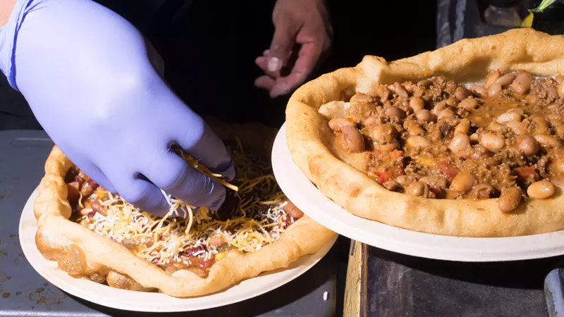 Image: Chef Renetto-Mario Etsitty loads two meat and bean chili Navajo tacos up with cheese, which he'll then melt with a torch.