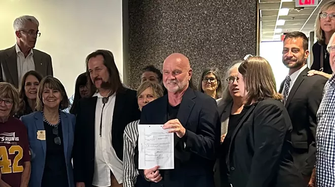 a man holds up a sheet of paper surrounded by other people