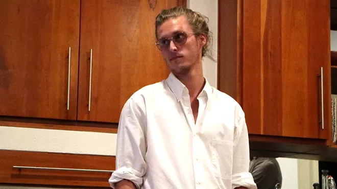a young man in glasses with his blond hair up in a bun