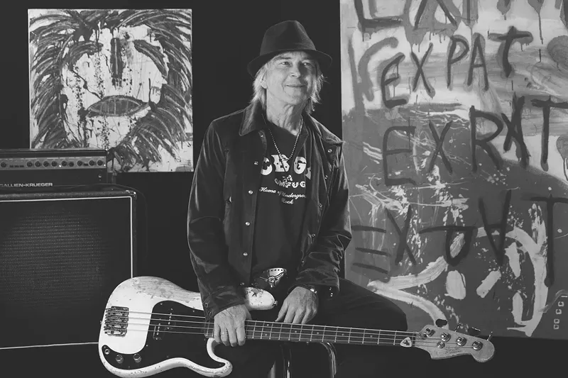 Image: The author with his trusty bass and some of his paintings. Steve Davis will read from his new book on August 22.