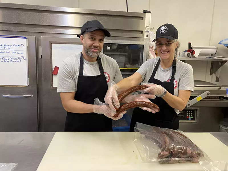 Image: The Meat Shop manager David Grant and owner Beth Wilson display the custom footlongs made for the Super Bowl Experience.