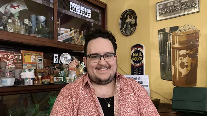 a man with black hair and glasses smiles