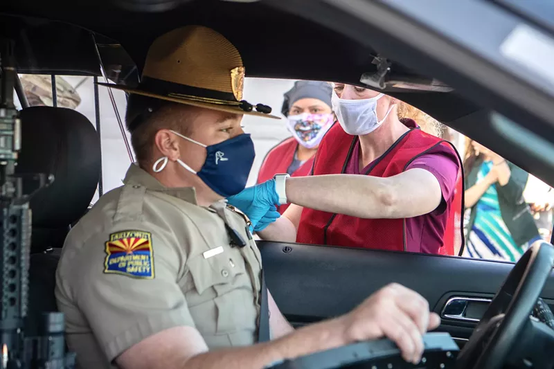 Image: A state trooper receives a vaccination from Arizona Department of Health Services head Cara Christ, Monday, January 11. The first day of the state's 24/7 vaccination site was reserved for law enforcement.