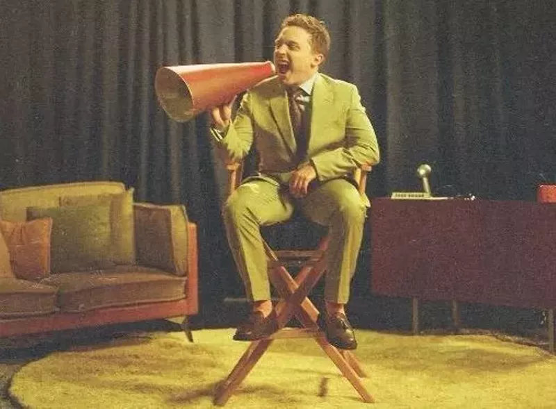 Image: A man sitting in a director's chair.