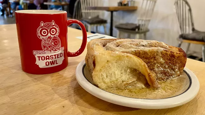 Coffee mug and cinnamon roll at Toasted Owl Cafe.