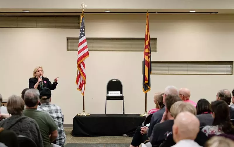 Image: Jodi Liggett of Planned Parenthood shows off the empty chair reserved for Senator Jeff Flake