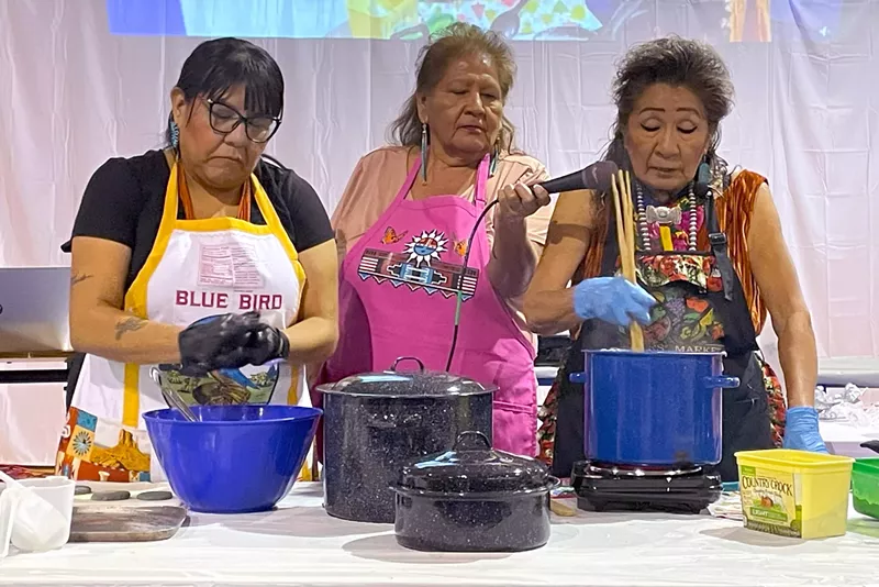 Image: Tennile Lopez (left) shapes blue corn dough while Bertha Etsitty (right) explains the process of blue corn mush on Nov. 25 at the Food Gathering Summit held by Diné College's Land Grant Office.