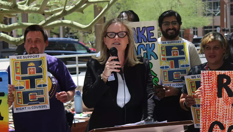Image: a woman in glasses speaks at a protest