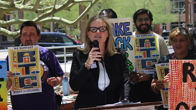a woman in glasses speaks at a protest