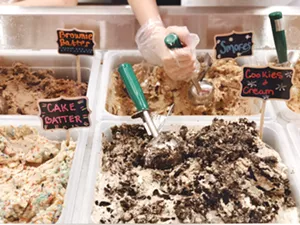 A staff member at Unbaked scoops raw cookie dough. All staff are trained to answer questions about each recipe. - MEAGAN MASTRIANI
