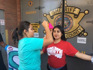 A supporter wipes sweat of Cynthia Díaz's face. Díaz, 23, was arrested in front of the Fourth Avenue County Jail for failure to disperse. - STEVEN HSIEH