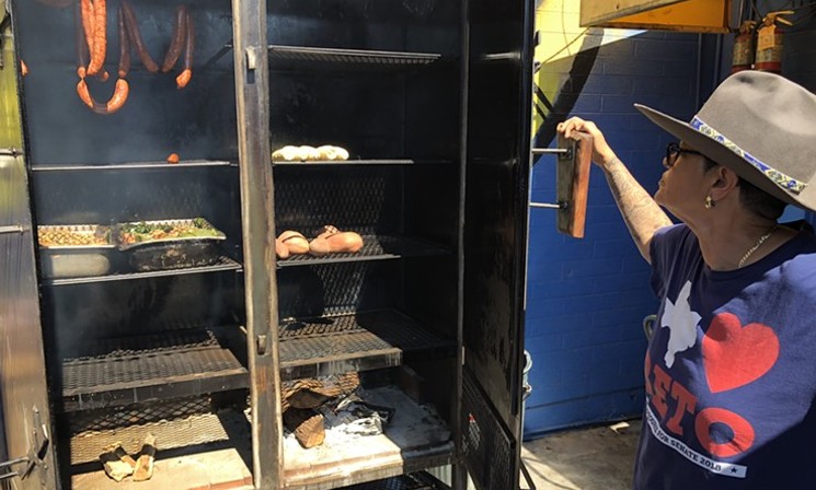 Esparza checking on meat and vegetables in her new upright smoker. - CHRIS MALLOY