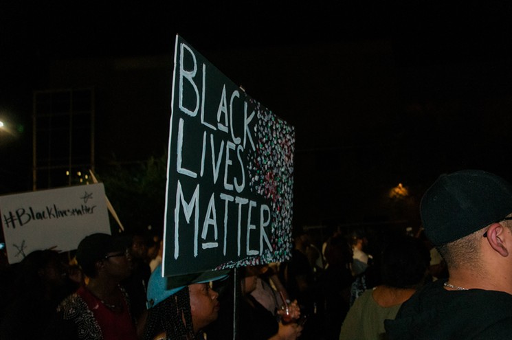 A protester holds a homemade "Black Lives Matter" sign. - ASH PONDERS