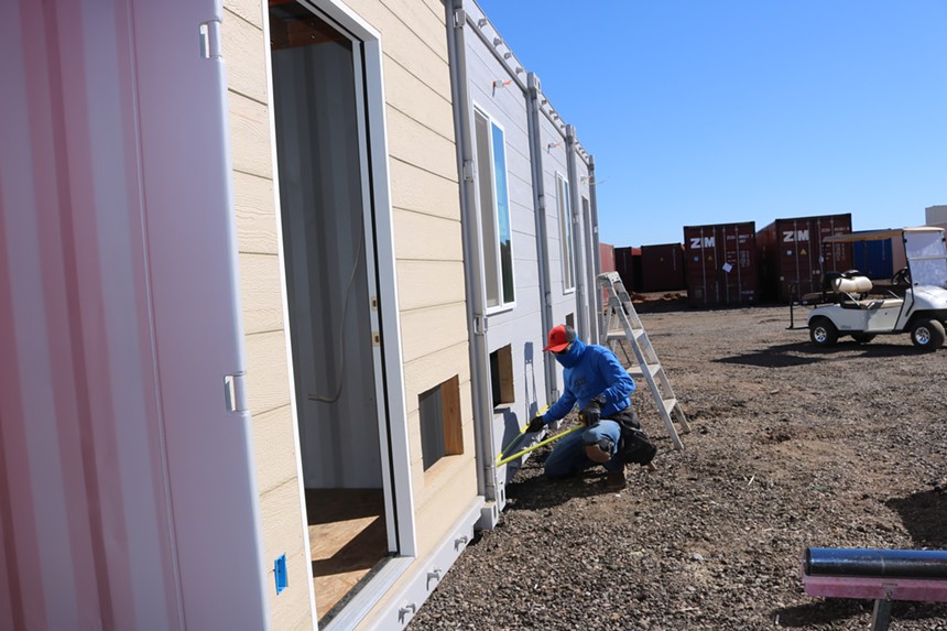 A worker is measuring material for The Jones Apartments, recycled shipping container homes built by Crosthwaite Custom Construction in Phoenix, Arizona. - MIKE MADRIAGA