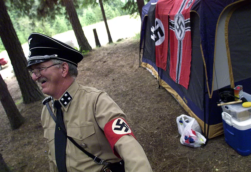 Tim Bishop, member of the National Socialists Movement, warms up by the fire of his campground at the Aryan Nations World Congress June 21, 2003 at Farragut State Park, Idaho. - JEROME A. POLLOS/GETTY IMAGES