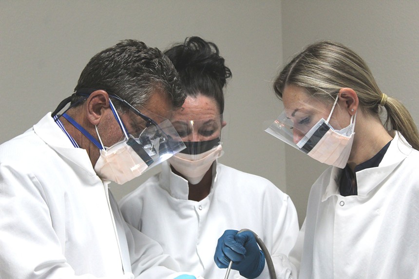 Dr. Leslie Fish (left) works with surgical assistants to prep the patient's mouth for a robot-assisted dental implant surgery in Chandler on Thursday morning. - ELIAS WEISS