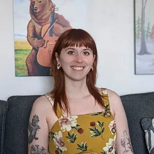 Woman smiles with long red hair and bangs