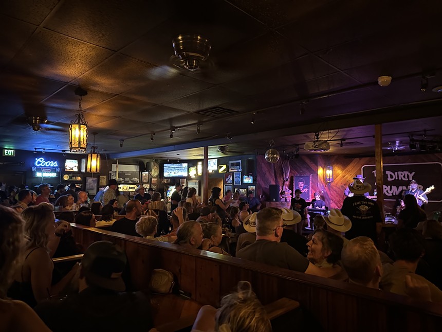A crowd of people watches a concert inside a bar.