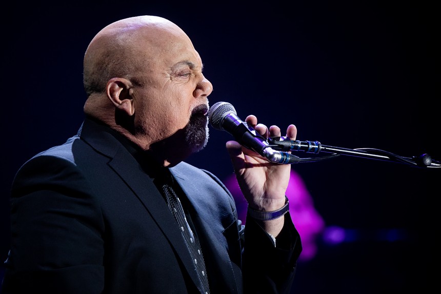 Rock 'n' roll legend Billy Joel singing into a microphone.