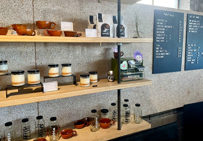 A shelf at Skoden Coffee & Tea displays mugs, bags of coffee and candles.