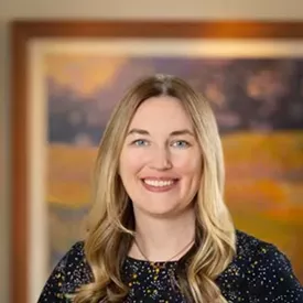 Headshot of a woman with long blonde hair smiling and looking into the camera