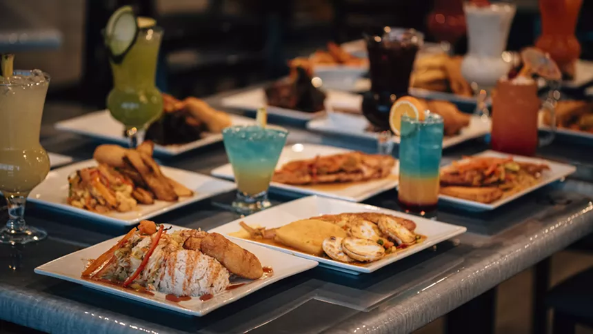 A spread of Jamaican dishes and glasses of rum punch.