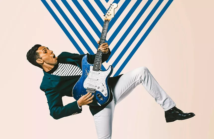 Man in blue coat playing a guitar.