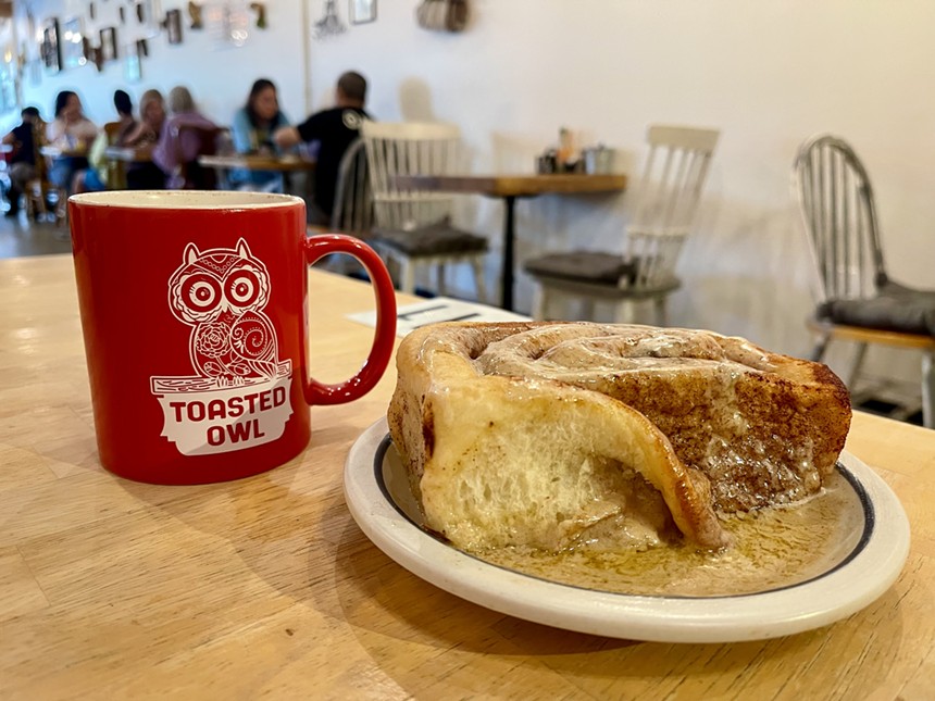 Coffee mug and cinnamon roll at Toasted Owl Cafe.