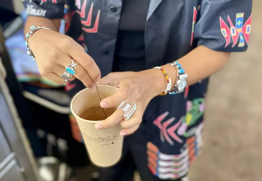 Natasha John stirs a paper cup of Diné tea.