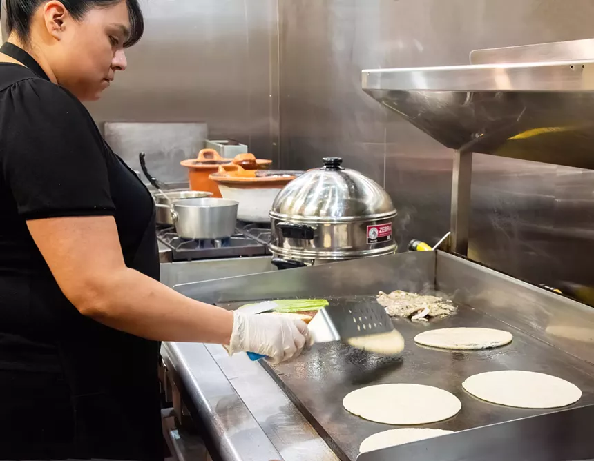 A woman cooks tortillas.
