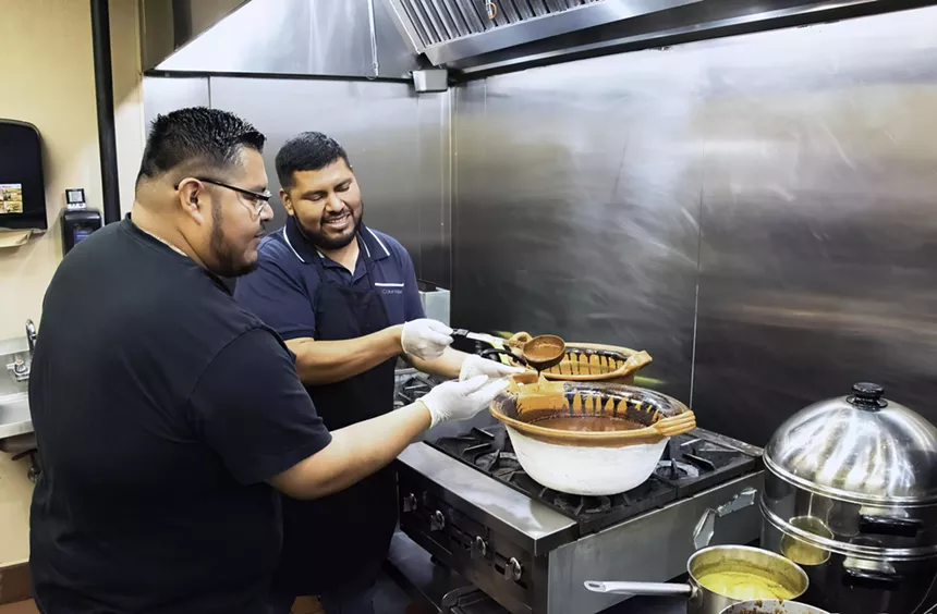 Two men at a stove.