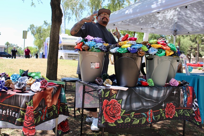 A man stands behind two tables selling bandana art.
