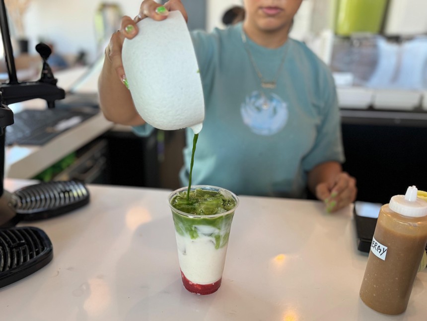 A barista pours matcha into a cup.