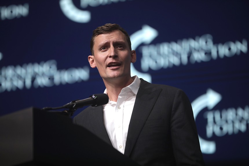 A man in a suit jacket speaking on a stage