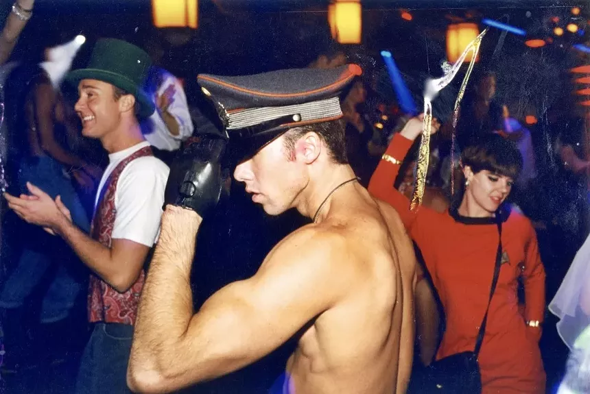 A nightclub patron wearing a military-style hat on a crowded dance floor.