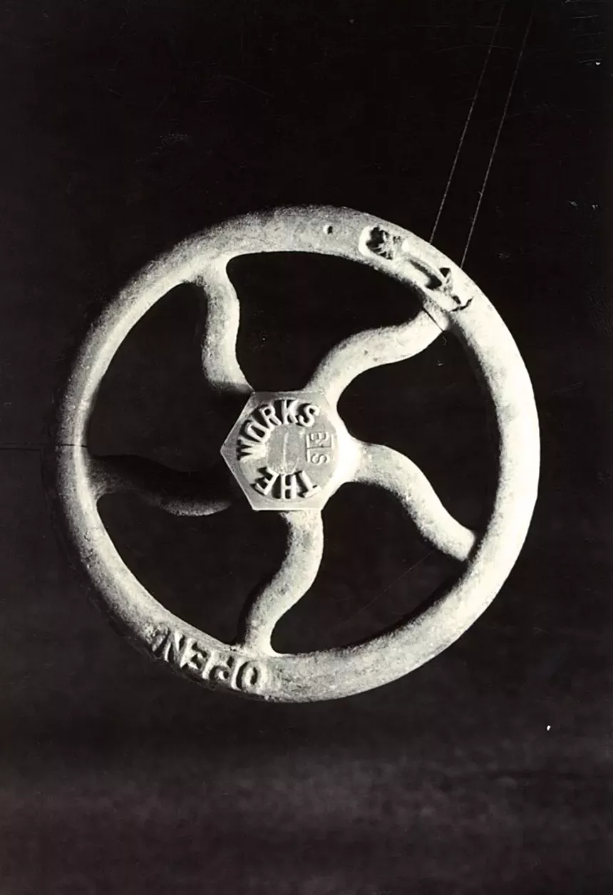 A black and white photo of an industrial pipe valve.