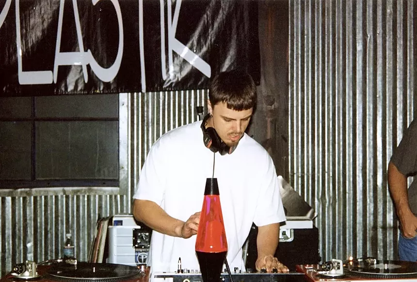A DJ standing behind a pair of record decks.