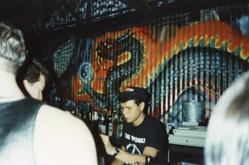 A bartender serves drinks behind a bar inside a nightclub.