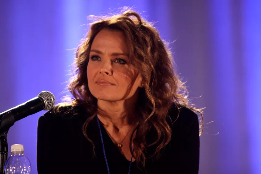 A woman with long brown hair sitting in a purple room.