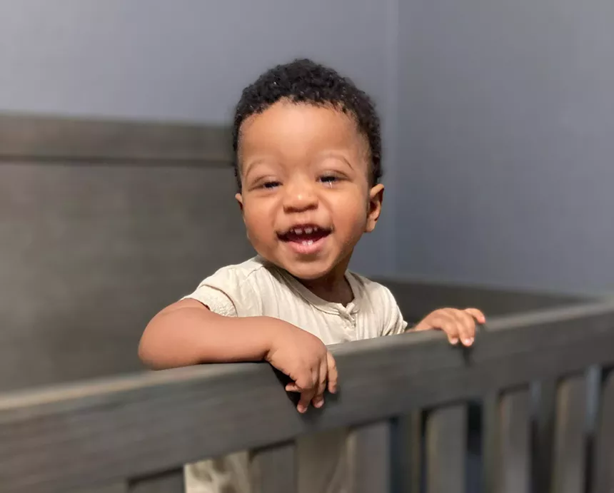 A smiling baby in a crib