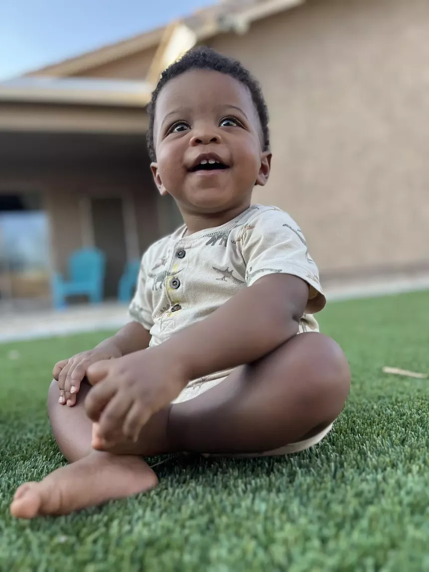A baby sitting outside on the grass.