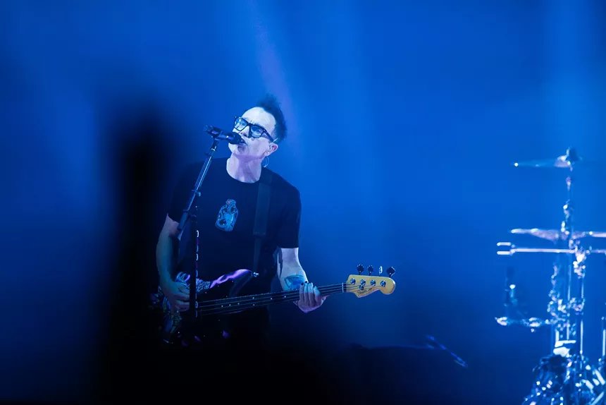 A man singing and playing bass.