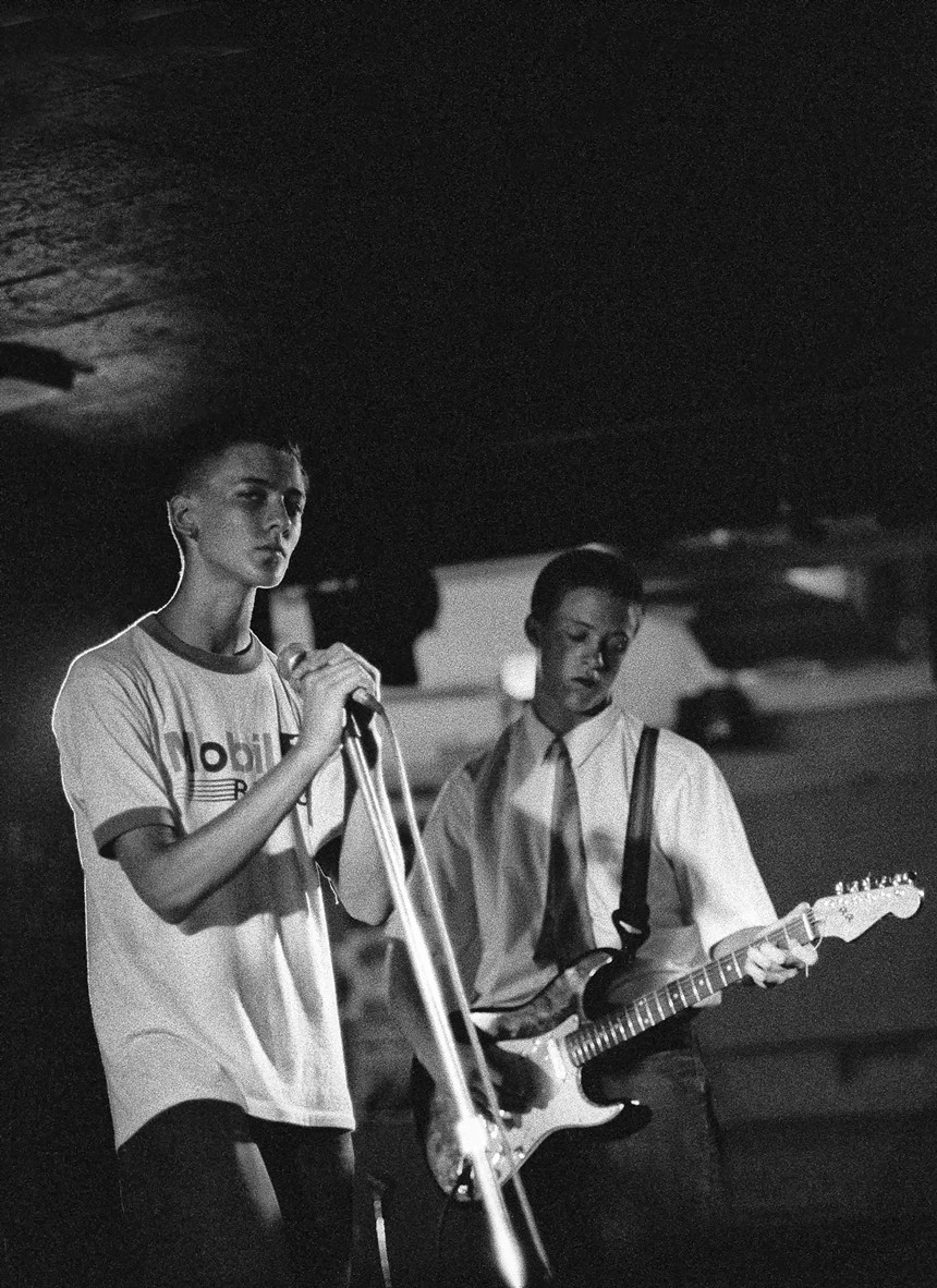A black and white photo of two teenage boys playing music.